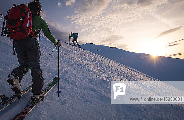 Zwei Personen bei Sonnenaufgang beim Skilanglauf in Island
