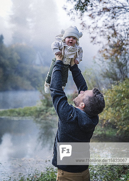 Ein Mann hält ein Baby in der Nähe eines Flusses