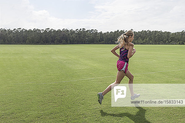 Teen girl cross country runner practicing sprints at soccer field