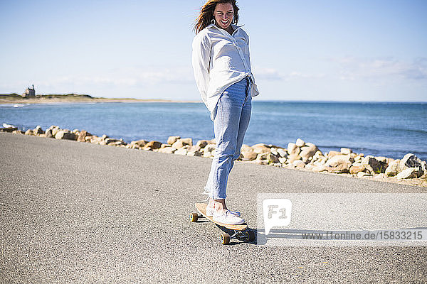 Junge Frau beim Longboard-Skateboarden auf Block Island