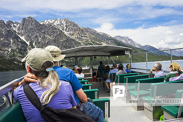 Menschen  die mit der Fähre auf dem Jenny Lake mit der Teton Range dahinter fahren
