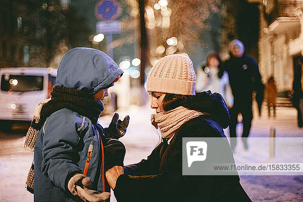 Mutter kommuniziert mit Sohn  während er auf der Straße seine Jacke zumachen muss
