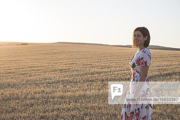 woman smiling in wheat field at sunset