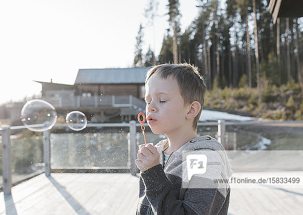 Junge bläst Blasen auf seinem Balkon zu Hause in Schweden