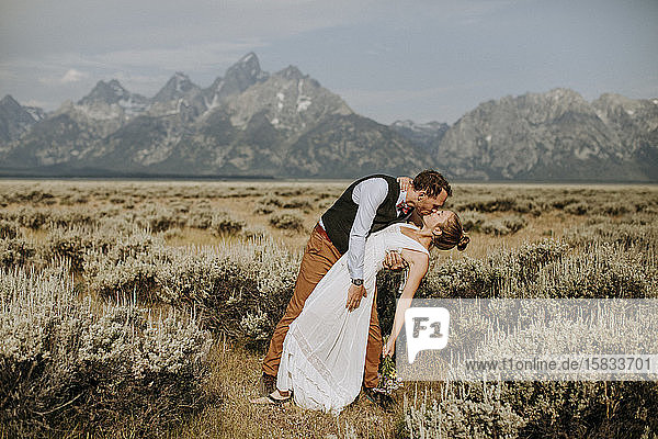 Groom dips bride for kiss in field in front of Grand Teton  Wyoming