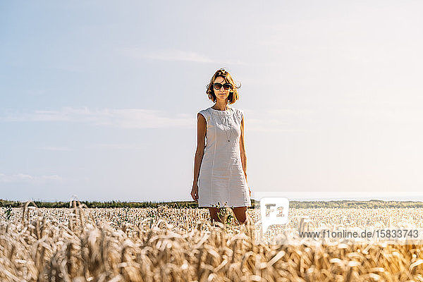 Frau in einem schönen weißen Kleid  die im goldenen Grasfeld steht
