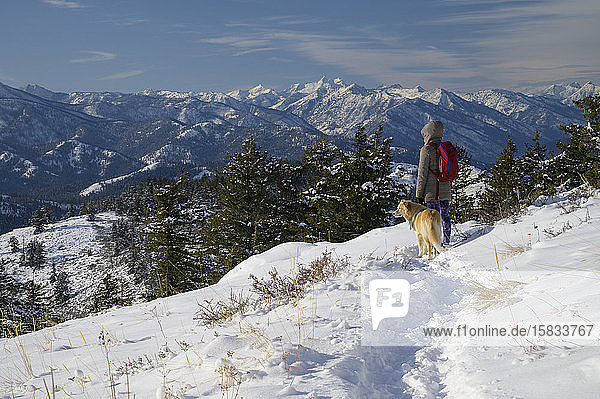 Wanderin und Hund blicken in die fernen Berge