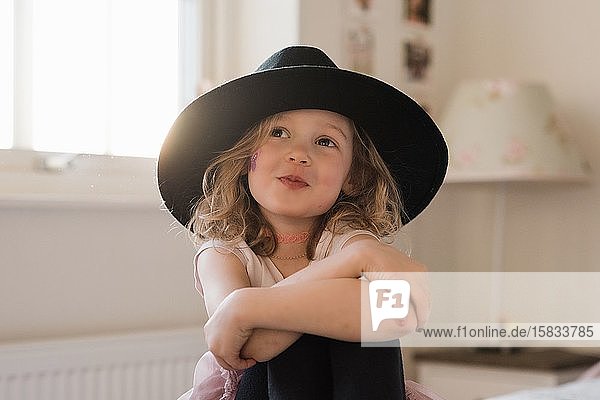 Porträt eines jungen Mädchens  das zu Hause mit Schmuck und einem Hut lächelt