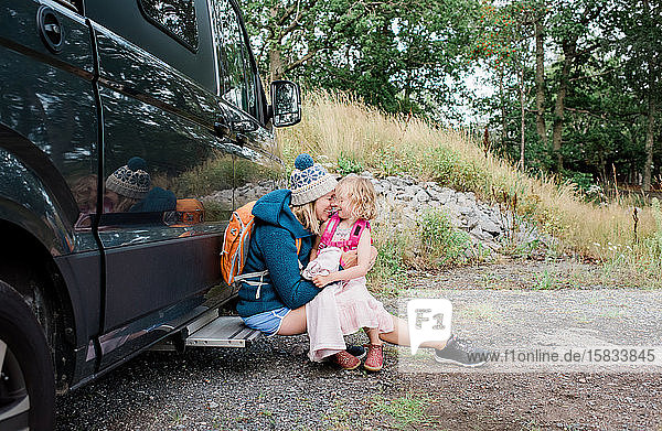mother and daughter hugging and laughing whist camping in a camper van