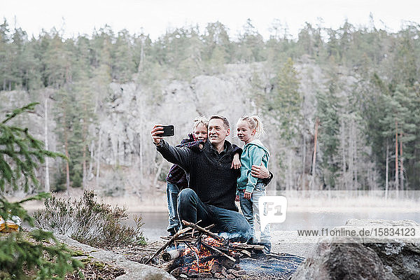 Vater fotografiert mit seinen Kindern am Lagerfeuer