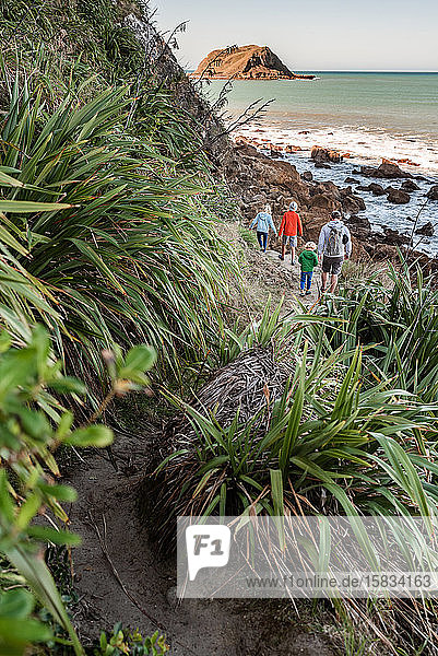Vater und Kinder wandern am Ozean in Neuseeland