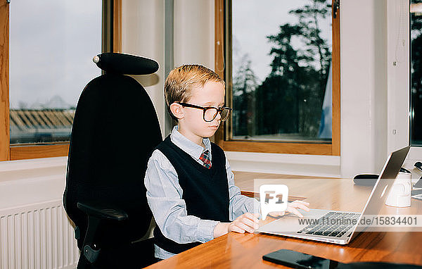 young boy working in his dads office working on a computer