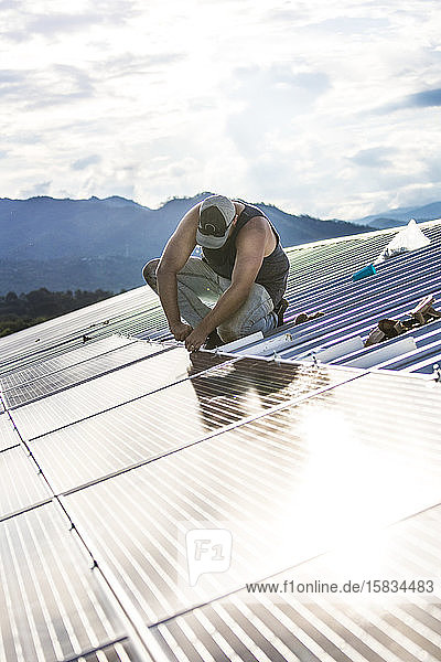 Arbeiter installiert Sonnenkollektoren auf dem Dach des Gebäudes.
