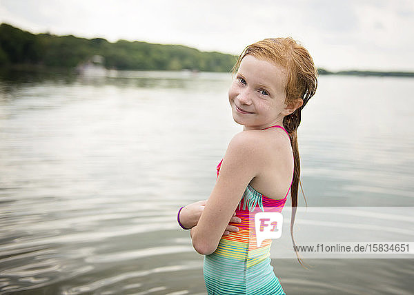 Junges rothaariges Mädchen im Badeanzug an einem See stehend