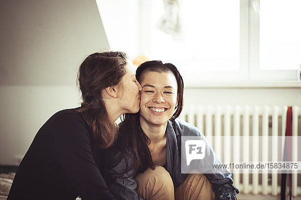 lesbisches Paar küsst sich auf die Wange und bleibt zu Hause in der Wohnung eingeschlossen