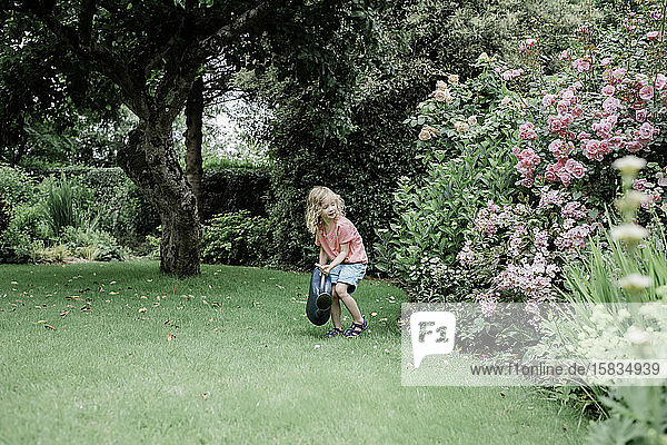 junges Mädchen gießt ihren Garten auf dem Land in England mit einer Gießkanne