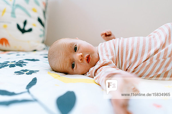 Closeup portrait of a baby girl laying on a colorful comforter