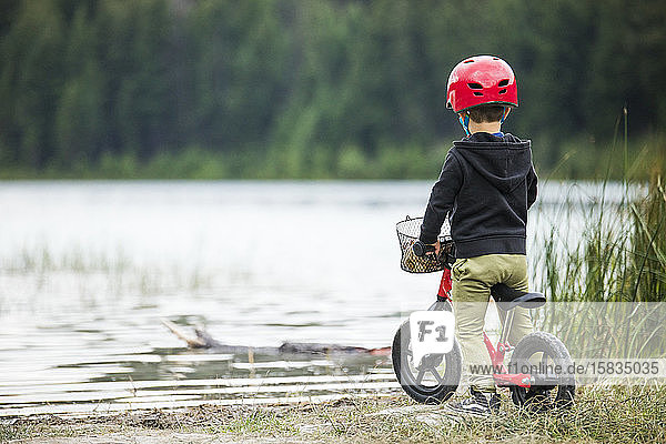 Rückansicht eines Jungen auf einem Balance-Rad mit Blick auf den See.