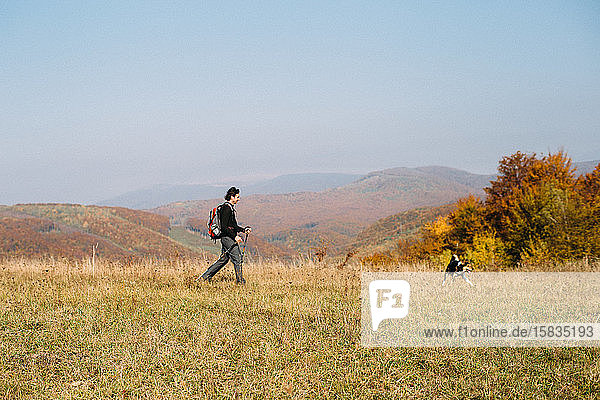 Mann mit Hund beim Wandern in den Herbstbergen