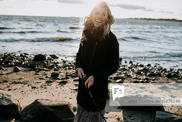 Porträt einer Frau  die im Winter am Strand lacht