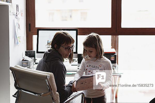 Schöne telearbeitende Mutter kümmert sich um ihre Kinder während sie im Wohnzimmer am Computer arbeitet
