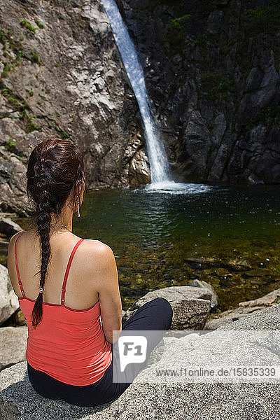 Frau sitzt an einem Wasserfall im Seroksan-Nationalpark