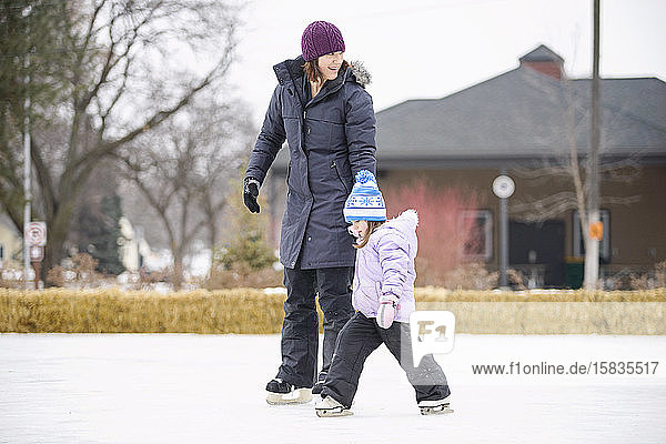 Mutter unterrichtet Tochter zum Schlittschuhlaufen