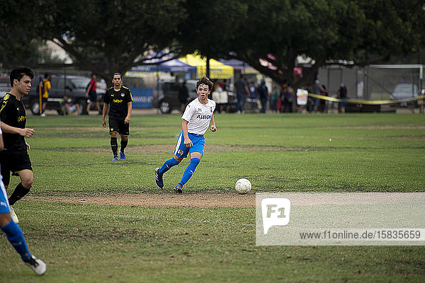 Teen soccer player dribbling the ball during a game