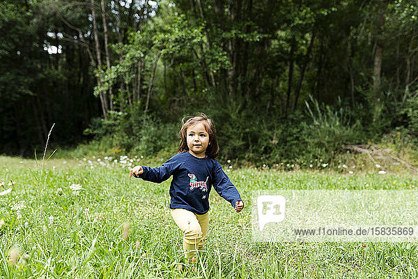 Carefree little girl running on meadow