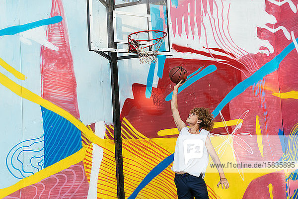 The rear view of a young boy shooting a basketball toward a hoop.