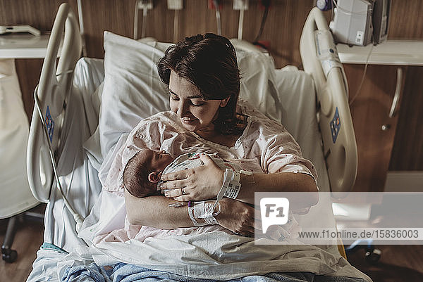 Mid view of mother in hospital bed looking at newborn son