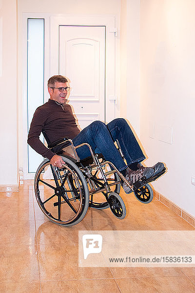 Ein Mann spielt mit einem Rollstuhl Balancieren und hat Spaß