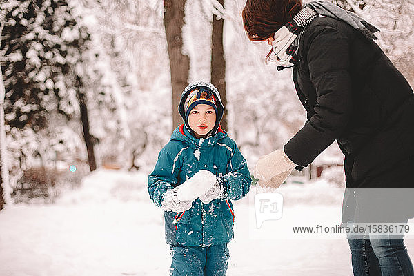 Mother and son playing with snow in winter