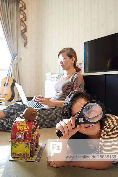 Ein Mädchen spielt in der Nähe einer Mutter  die mit einem Laptop arbeitet