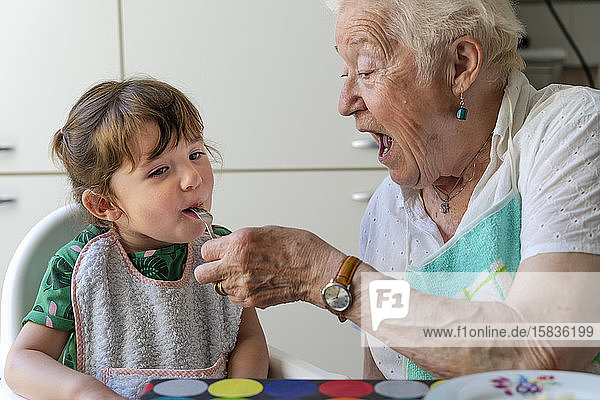 Großmutter füttert Enkelin in der Küche