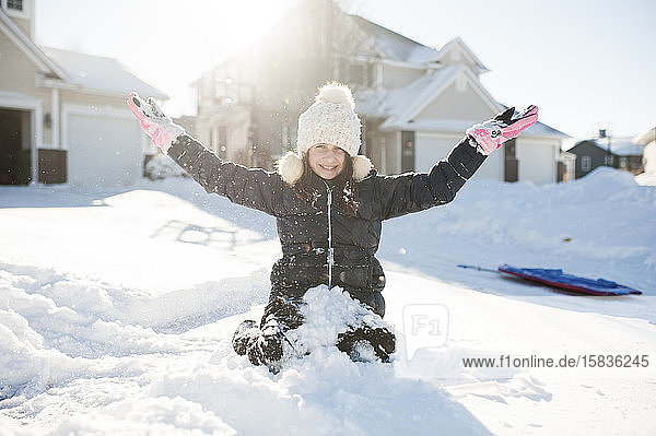 Mädchen im Alter von 10-12 Jahren amüsiert sich im Schnee vor dem Haus