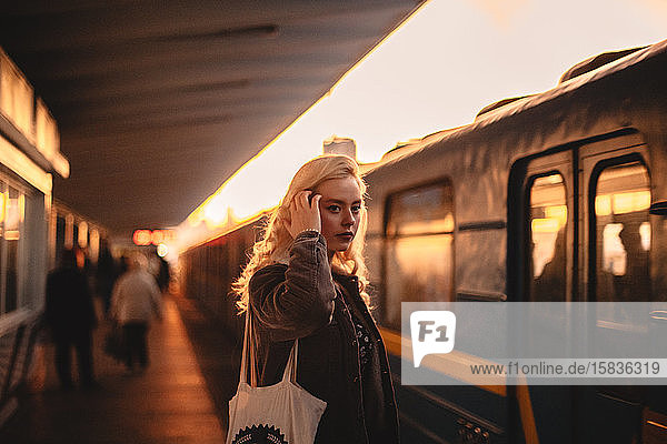 Young woman standing at subway station while train arriving