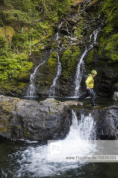 Mann geht beim Canyoning über einen kleinen Wasserfall.