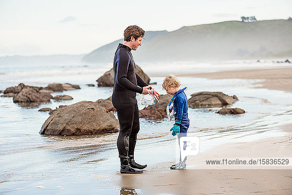 Father and son in wetsuits on beach in New Zealand