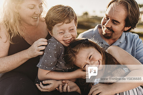 Detailaufnahme einer vierköpfigen Familie die bei Sonnenuntergang am Strand spielt