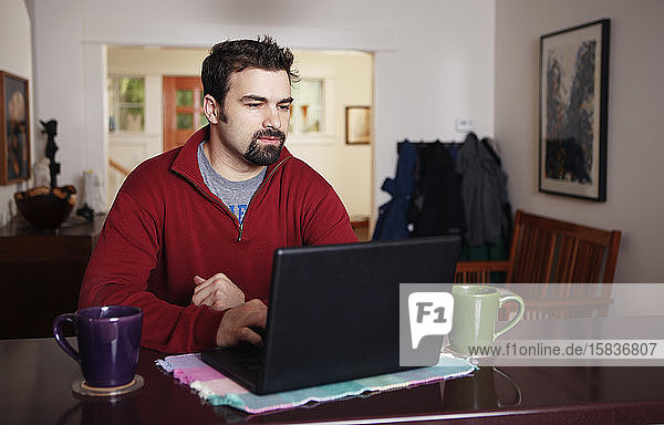 Mann arbeitet von zu Hause am Laptop