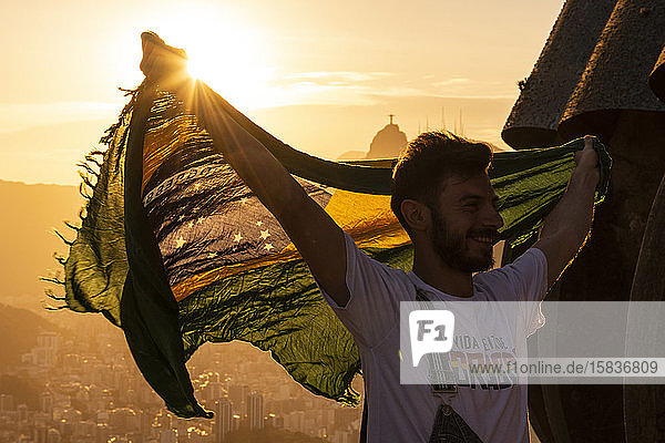Schöne Szene eines Touristen auf dem Zuckerhut mit der brasilianischen Flagge