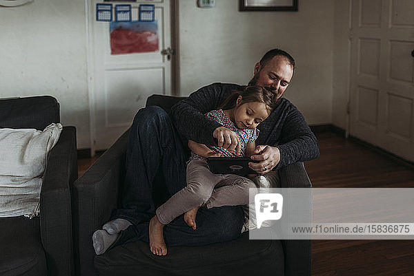 Vater und kleine Tochter spielen während der Isolation auf dem Tablett