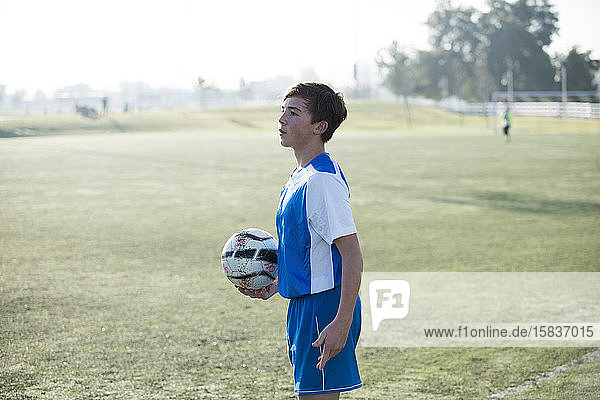 Teenager-Fussballspieler hält Ball und ist bereit für einen Einwurf
