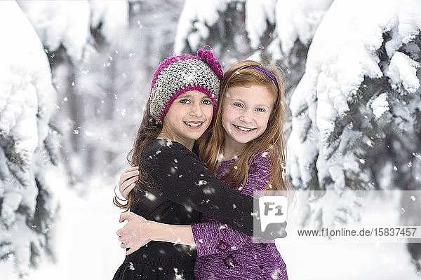 Two Young Girls Hugging in Beautiful Fresh Snow Scene