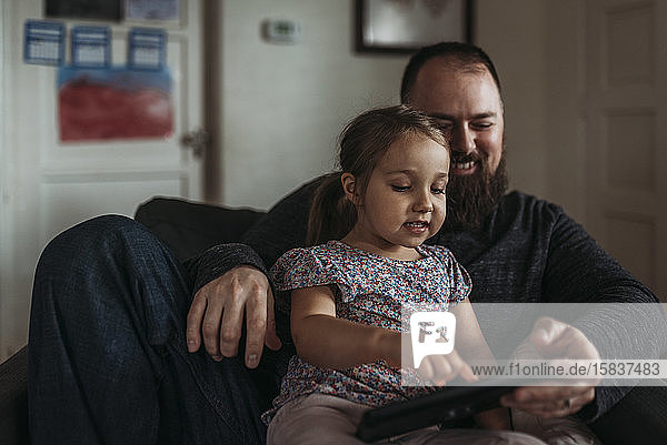 Nahaufnahme eines Vaters und einer kleinen Tochter  die während der Isolation auf einem Tablett spielen