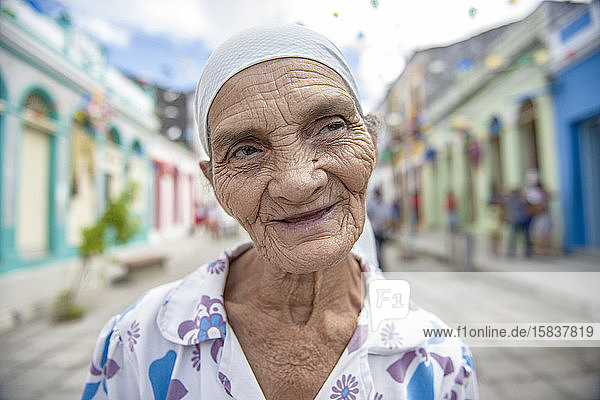 Old woman smiles in a colorful colonial street in northeast Brazil