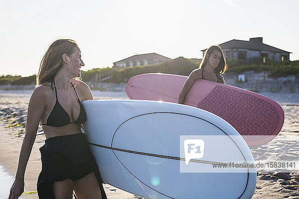 Wasserfreundinnen surfen gemeinsam bei Sonnenuntergang