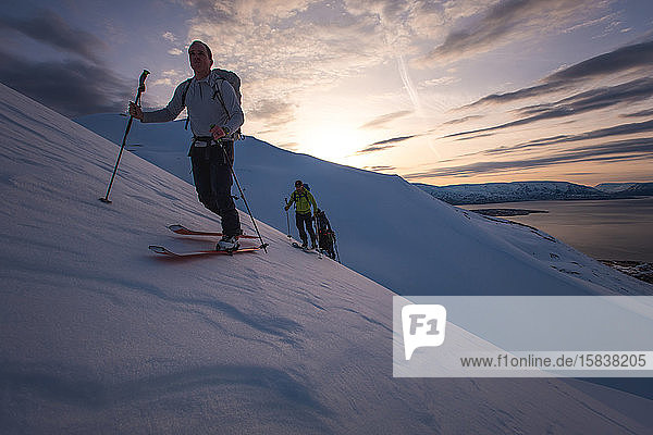 Group of people backcountry skiing at sunrise in Iceland