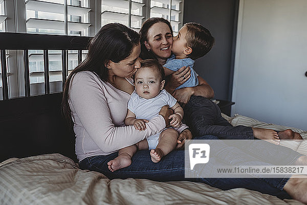 Glückliche nicht-traditionelle Familie mit zwei Müttern und Kindern  die zu Hause kuscheln